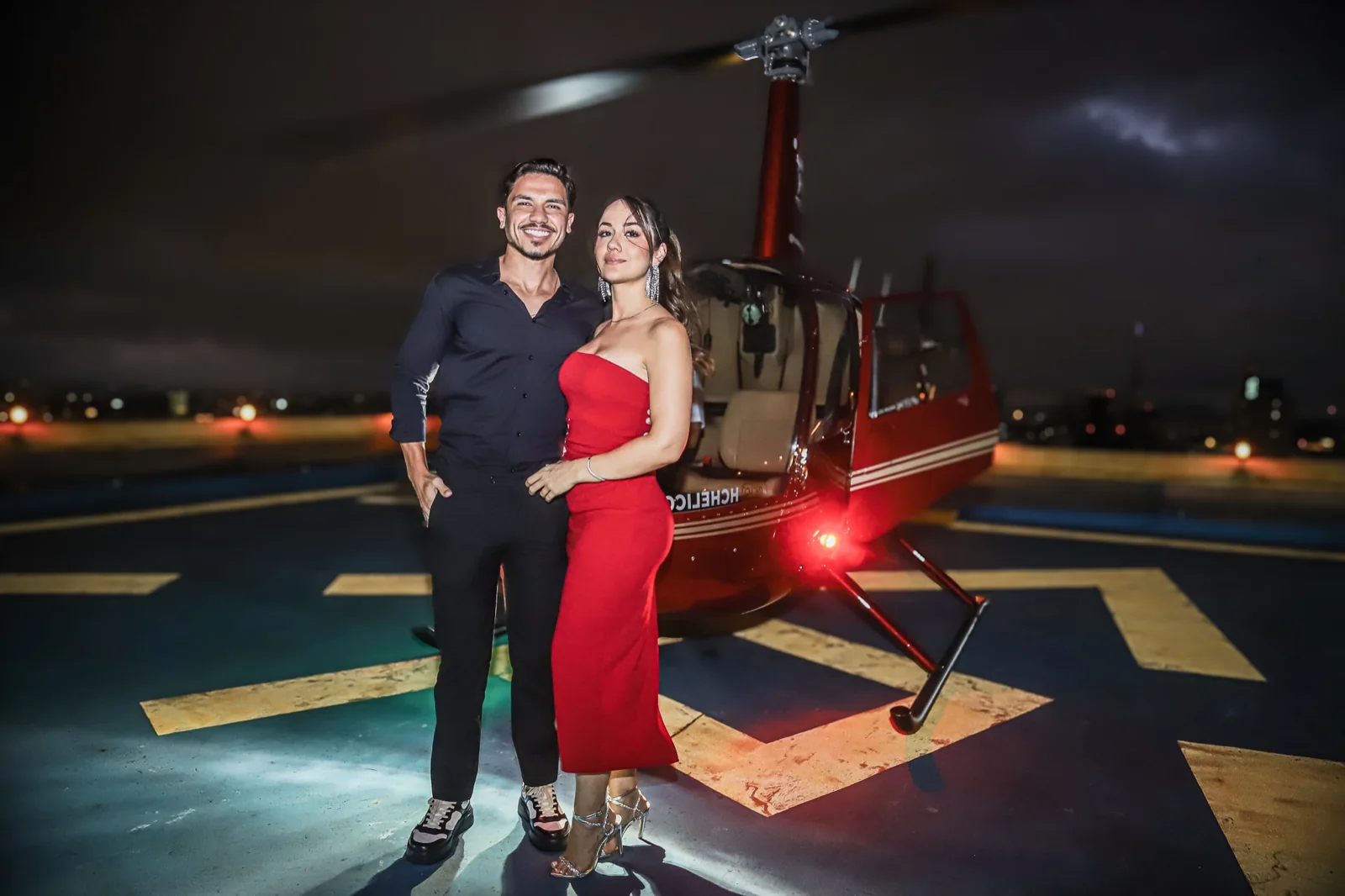 Casal em traje de celebração ao lado do helicóptero à noite